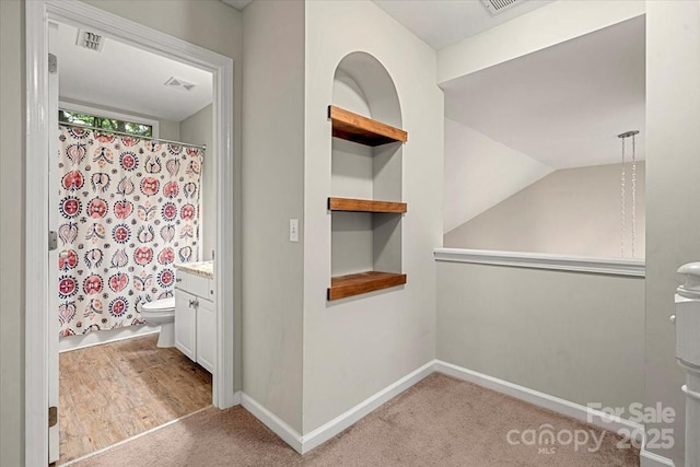 bathroom featuring a shower with shower curtain, toilet, vanity, baseboards, and vaulted ceiling