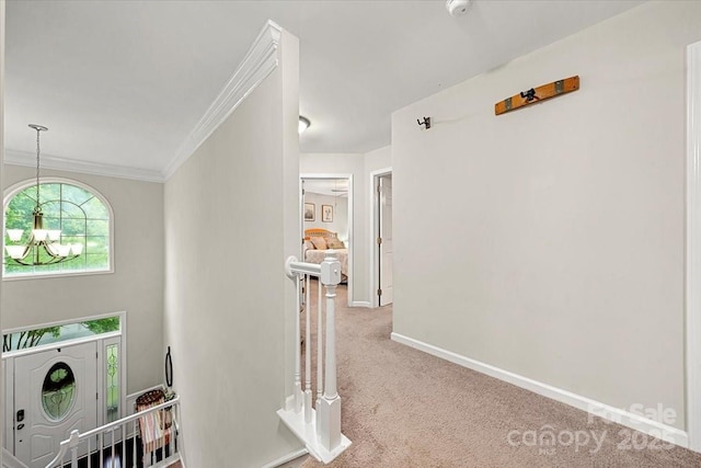 hall with carpet, crown molding, baseboards, and an upstairs landing