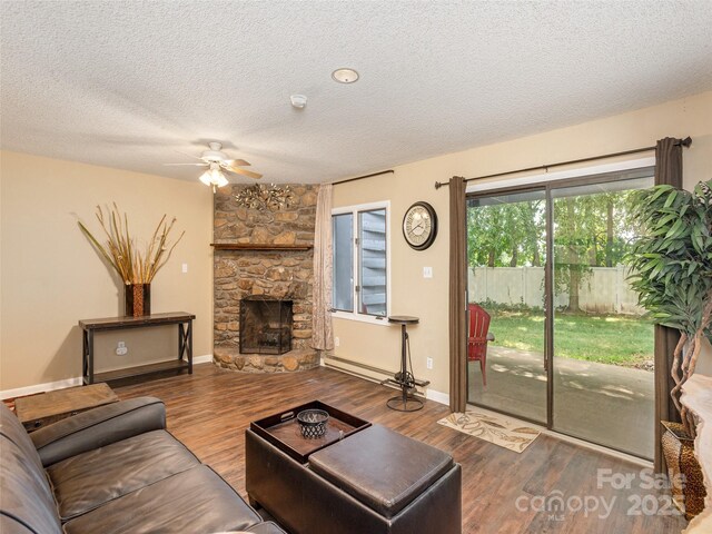 23 Hollybrook Dr, Asheville, NC 28803 - living area featuring wood finished floors, a stone fireplace, baseboards, a textured ceiling, and a ceiling fan