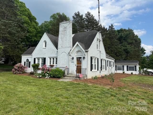 english style home featuring a chimney and a front yard