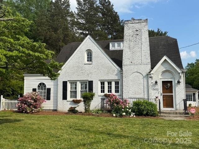 view of front of home featuring fence, a chimney, and a front lawn