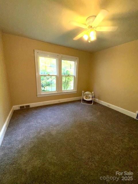 spare room featuring ceiling fan, visible vents, baseboards, and dark colored carpet