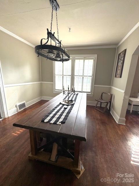 dining area featuring crown molding, baseboards, visible vents, and wood finished floors
