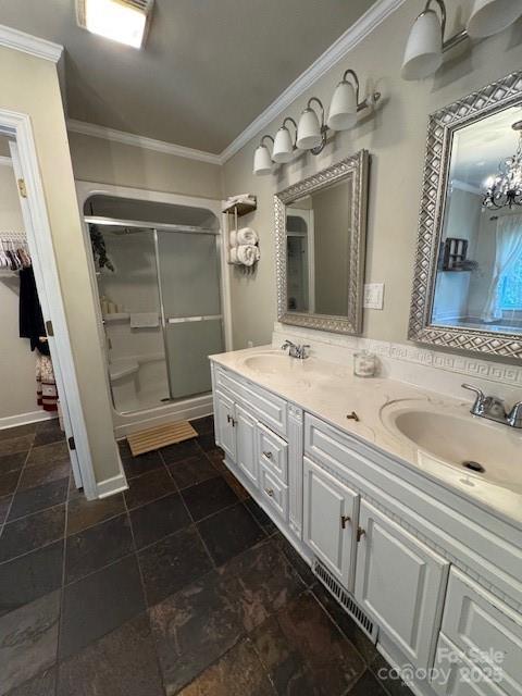 full bath featuring crown molding, a sink, a stall shower, and double vanity
