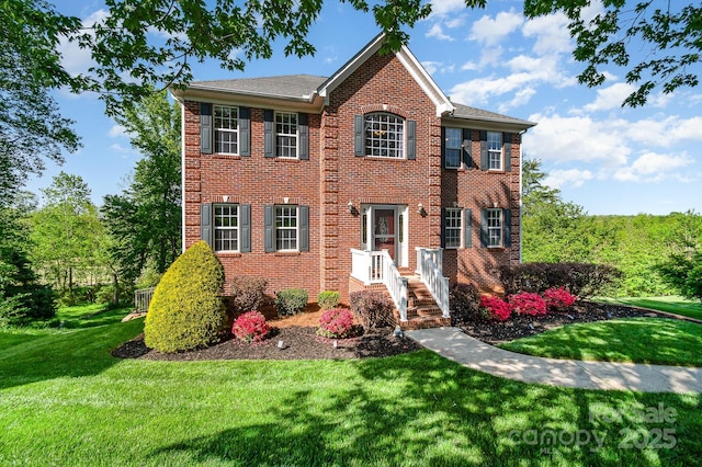 colonial house featuring brick siding and a front yard