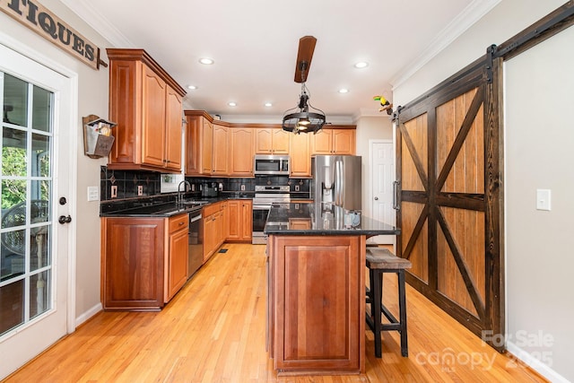 kitchen featuring backsplash, a barn door, appliances with stainless steel finishes, and ornamental molding