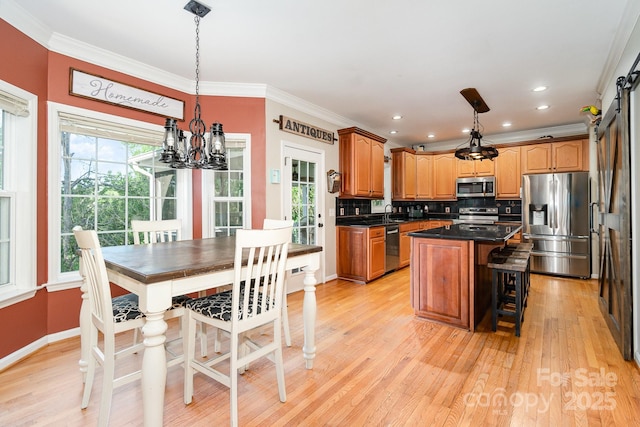 kitchen with dark countertops, light wood-style floors, a center island, a chandelier, and appliances with stainless steel finishes