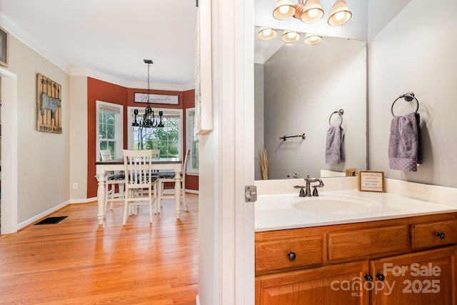 bathroom featuring an inviting chandelier, crown molding, visible vents, wood finished floors, and baseboards