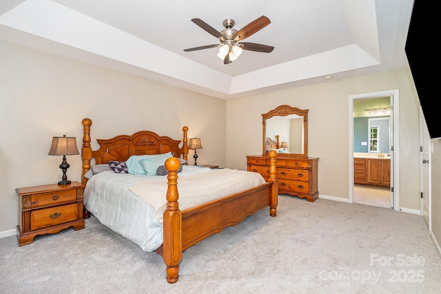 bedroom featuring baseboards, a tray ceiling, connected bathroom, and light colored carpet