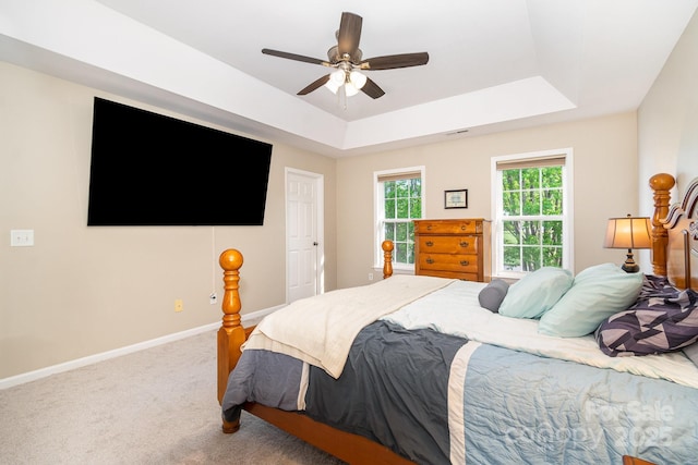 carpeted bedroom with baseboards, a ceiling fan, a raised ceiling, and visible vents