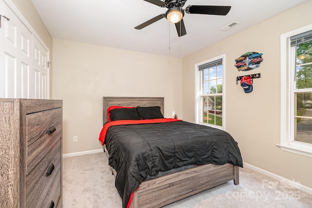 carpeted bedroom with visible vents, baseboards, and multiple windows