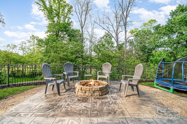view of patio featuring fence, a trampoline, and an outdoor fire pit