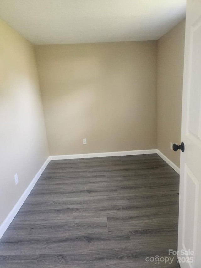 empty room with baseboards and dark wood-type flooring
