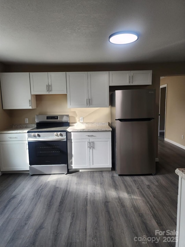 kitchen with dark wood-style flooring, baseboards, a textured ceiling, white cabinets, and stainless steel appliances