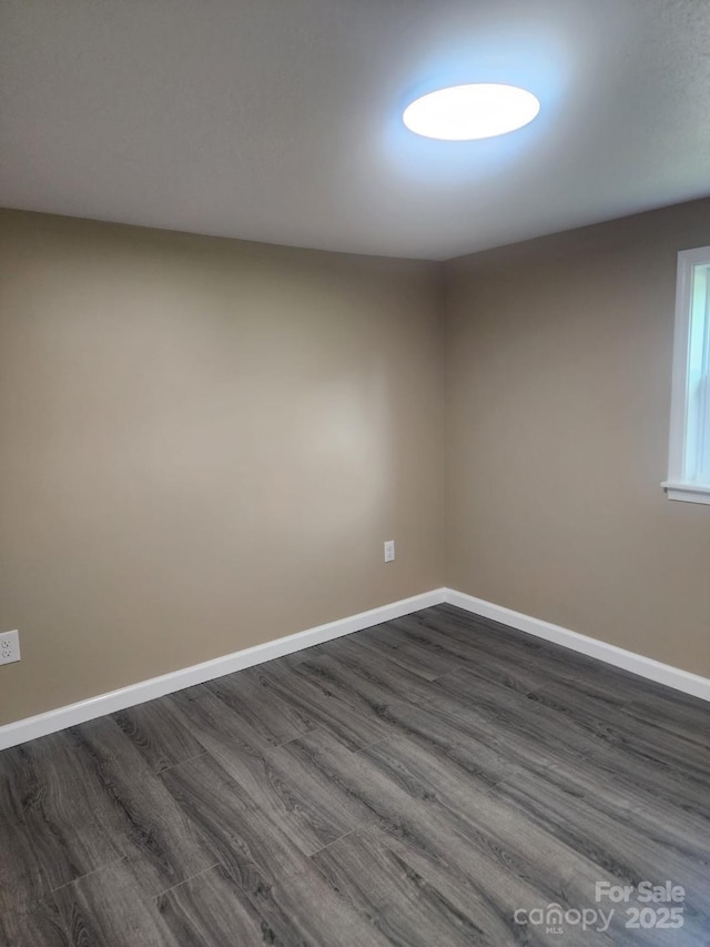 unfurnished room featuring baseboards and dark wood finished floors