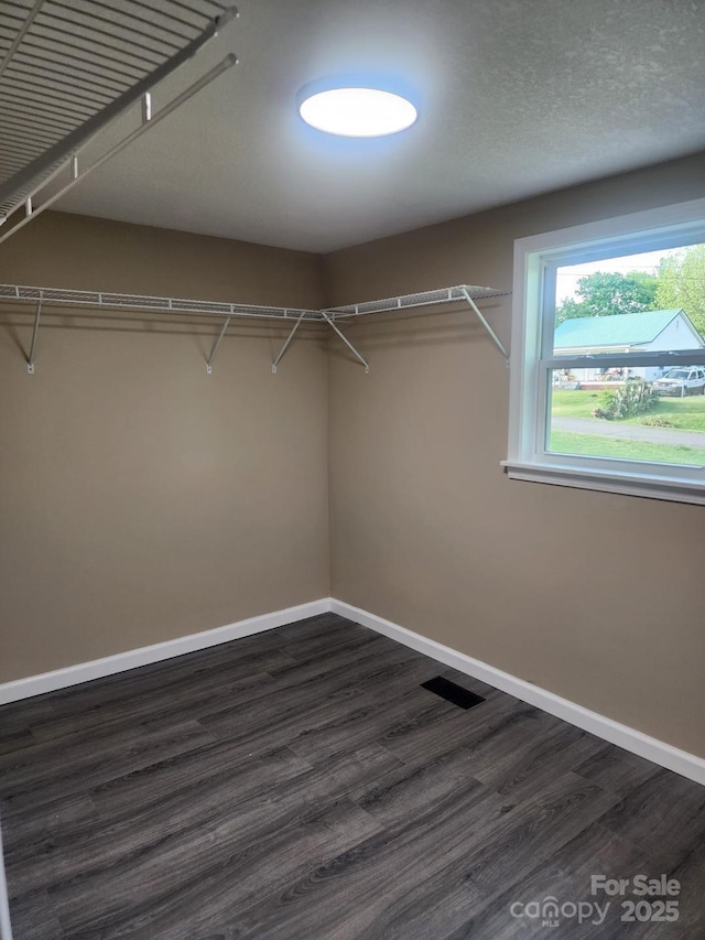 walk in closet with dark wood-style flooring and visible vents