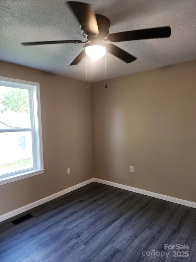 spare room with a ceiling fan, dark wood-type flooring, a textured ceiling, and visible vents