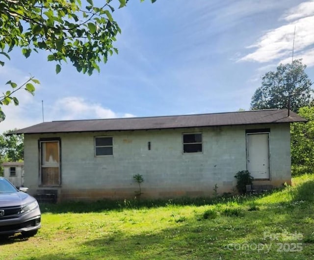 rear view of property featuring concrete block siding and a lawn