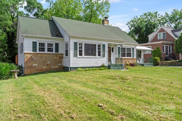 view of front facade featuring a chimney, a front yard, and stone siding