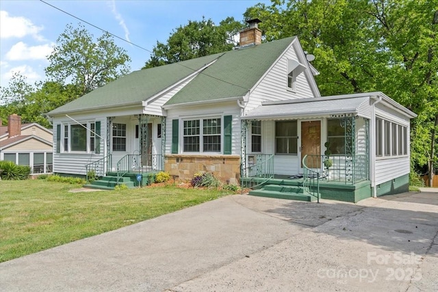 view of front of home with a chimney, a porch, stone siding, and a front yard