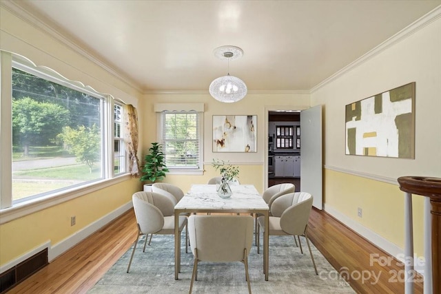 dining room with ornamental molding, wood finished floors, and visible vents