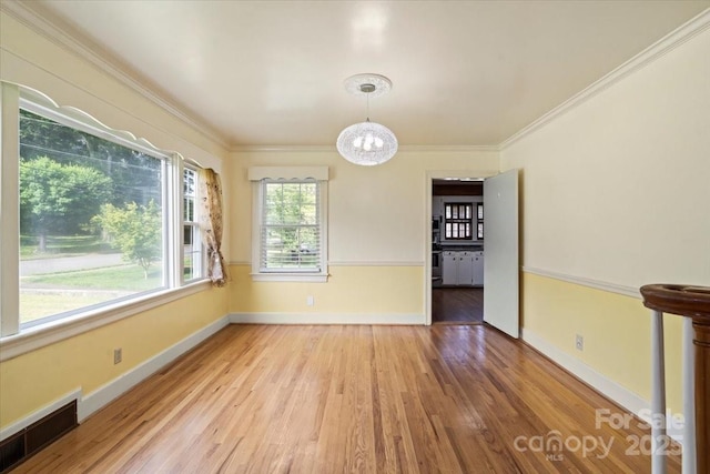 unfurnished dining area with visible vents, ornamental molding, wood finished floors, and a notable chandelier
