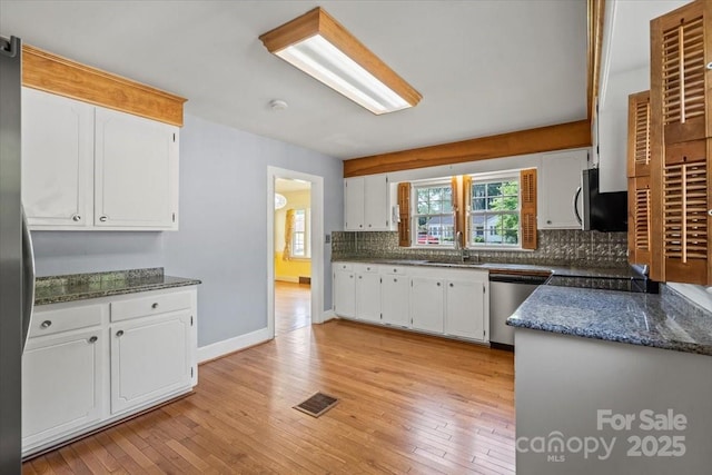 kitchen with backsplash, visible vents, a sink, light wood-style floors, and stainless steel appliances