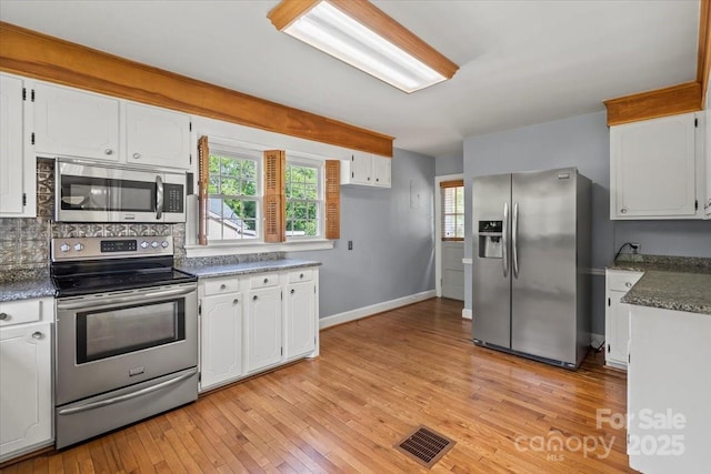 kitchen featuring visible vents, appliances with stainless steel finishes, tasteful backsplash, white cabinets, and light wood finished floors