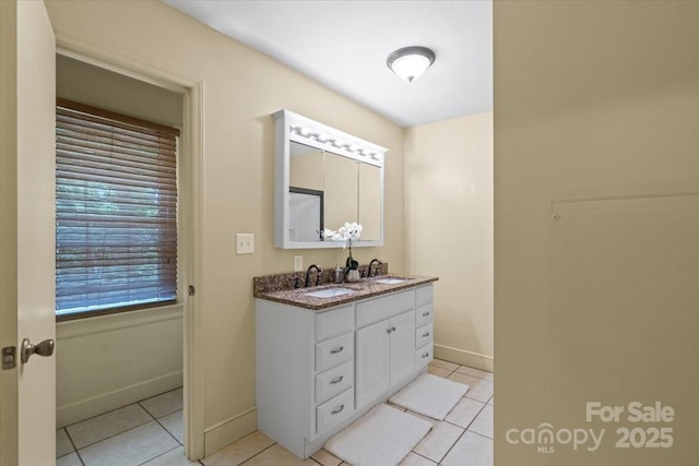 full bath featuring a sink, tile patterned floors, baseboards, and double vanity