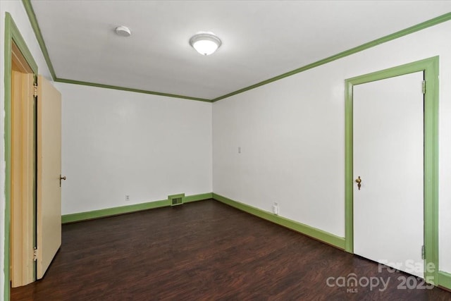 unfurnished bedroom featuring visible vents, ornamental molding, dark wood finished floors, and baseboards