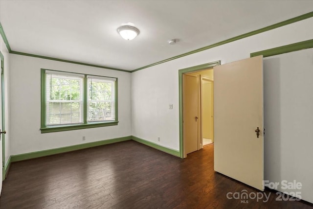 spare room featuring crown molding, baseboards, and wood finished floors