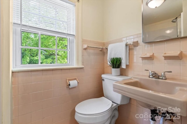 bathroom featuring a sink, tile walls, toilet, and a wealth of natural light