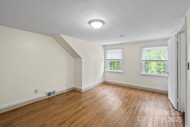 additional living space with baseboards, light wood-type flooring, and visible vents