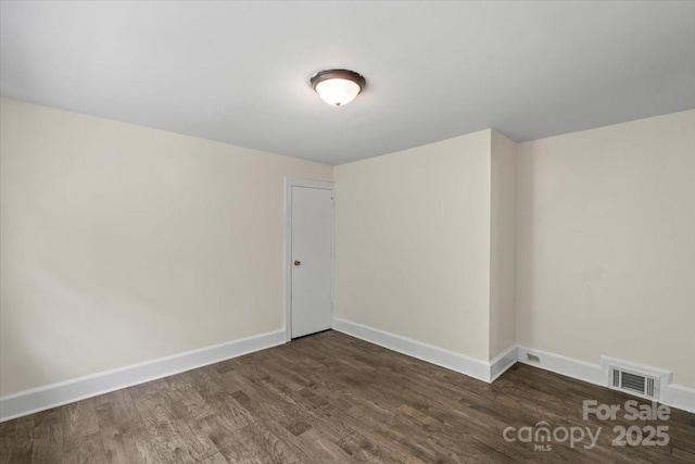 empty room featuring visible vents, baseboards, and wood finished floors