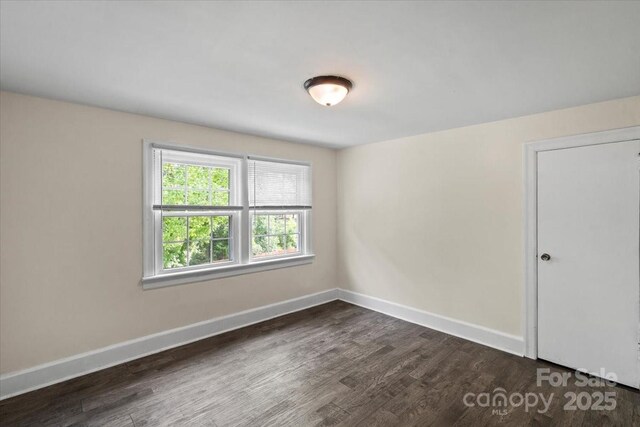 unfurnished room with baseboards and dark wood-style floors