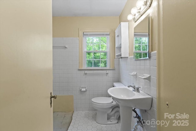 bathroom featuring tile patterned floors, toilet, and tile walls
