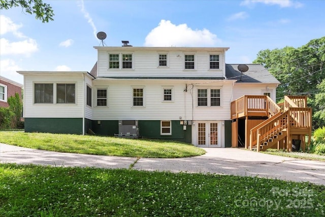 view of front of property featuring a front yard, a wooden deck, french doors, and stairway