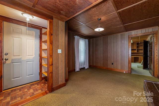 carpeted spare room with baseboards, wood walls, and wood ceiling