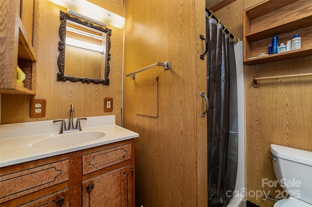 bathroom with wooden walls, vanity, toilet, and curtained shower