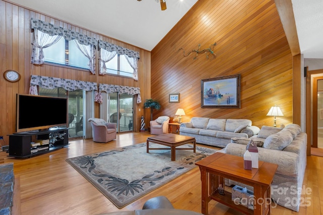 living room featuring wooden walls, high vaulted ceiling, and wood finished floors
