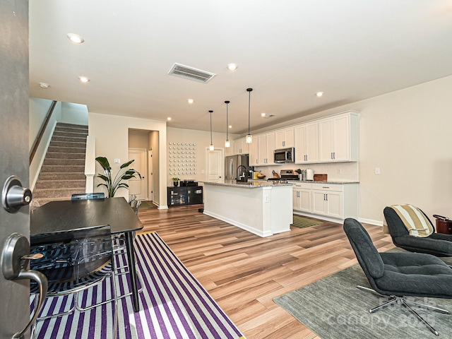 living area featuring light wood-style floors, visible vents, baseboards, and recessed lighting