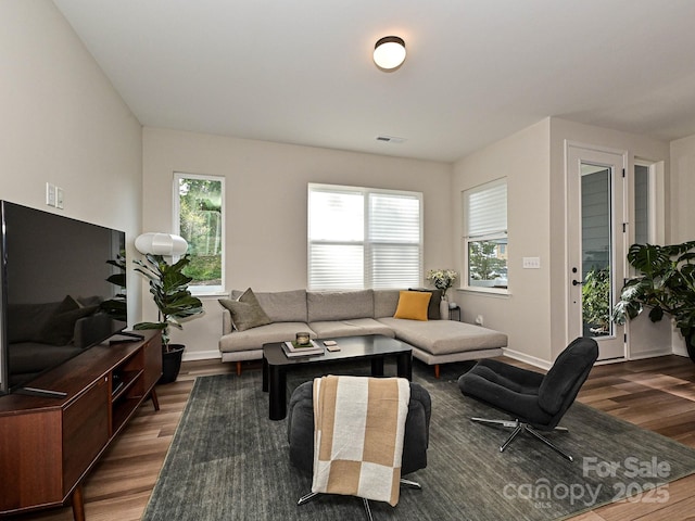 living room featuring baseboards, a wealth of natural light, dark wood finished floors, and visible vents
