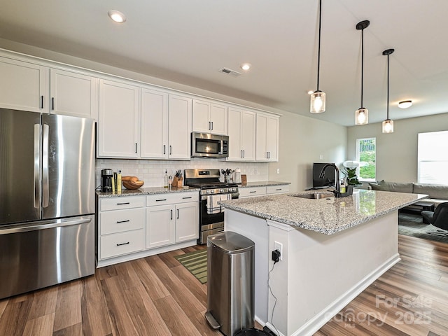 kitchen with stainless steel appliances, visible vents, dark wood-style floors, and a sink