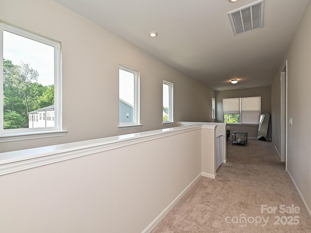hallway with baseboards, recessed lighting, light carpet, and visible vents