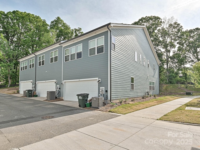 view of property exterior with central air condition unit and an attached garage