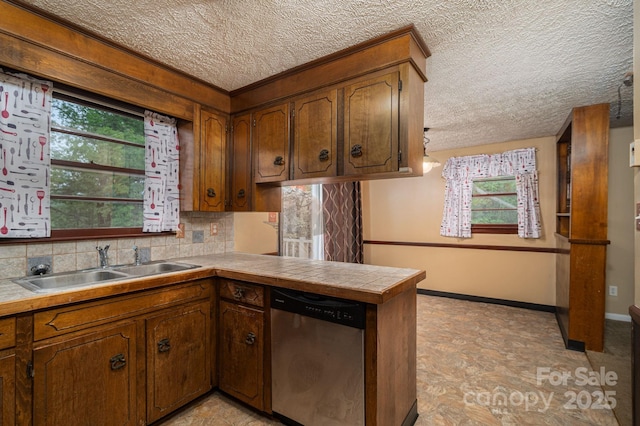 kitchen featuring stainless steel dishwasher, decorative backsplash, a peninsula, a textured ceiling, and a sink