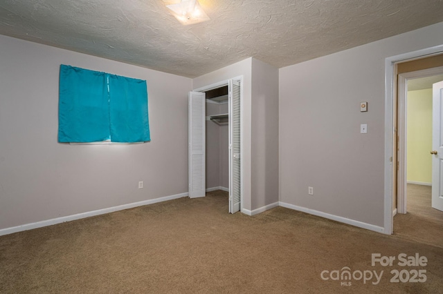 unfurnished bedroom featuring carpet floors, a textured ceiling, baseboards, and a closet