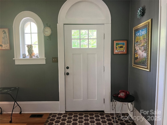 doorway to outside featuring a healthy amount of sunlight, baseboards, wood finished floors, and visible vents