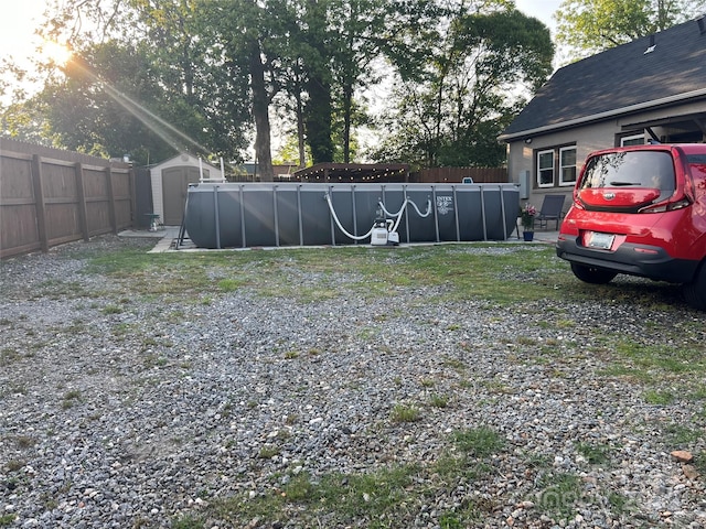 view of yard featuring a fenced backyard, a fenced in pool, an outbuilding, and a shed