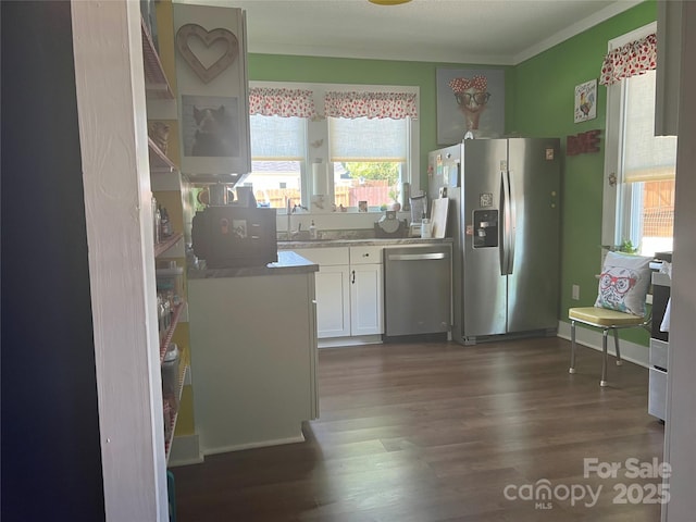 kitchen with crown molding, dark wood-type flooring, light countertops, white cabinets, and stainless steel appliances